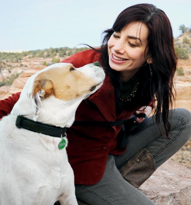 woman sitting with larger white and brown dog at edge of canyon vista