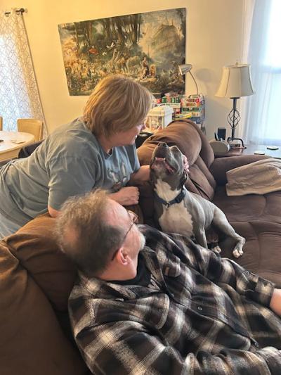 Jessa the dog at home on the couch with John and Tari