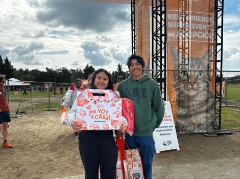 Two people, with one holding a cat carrier, after adopting at the Best Friends Super Adoption in Los Angeles