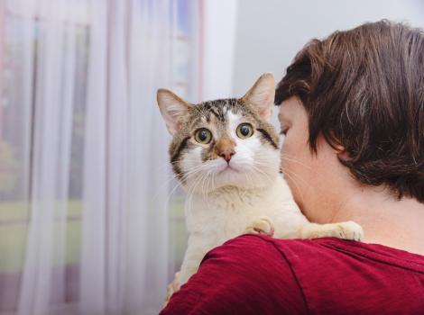 Person holding a cat over her shoulder