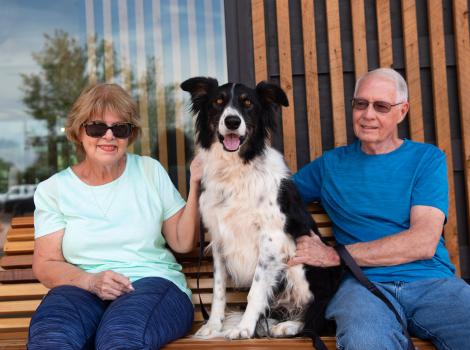 Sego the dog sitting on a bench between Sandy and Richard Garrett