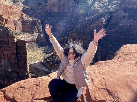 Tara Pope on a rock cliff with arms outstretched