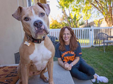 Aragon the dog in the foreground with a smiling person behind him, both outside in a yard