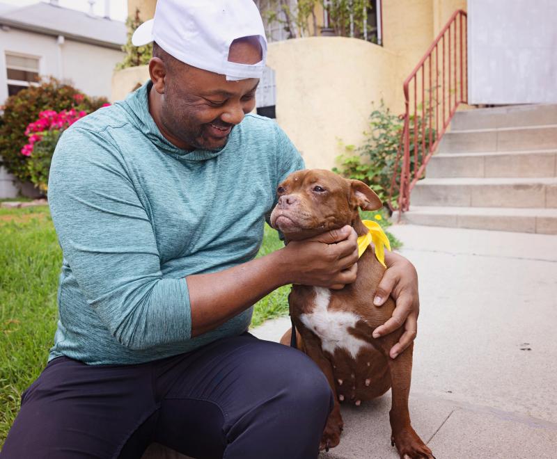 Smiling person sitting with a dog outside on some steps